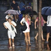 Vecinos de Murcia transitan bajo la lluvia durante una tormenta de verano.