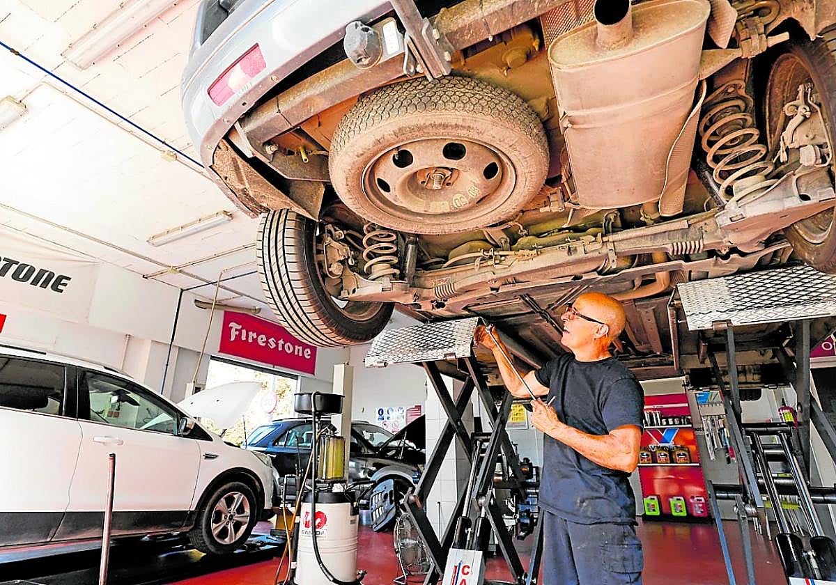 Un mecánico revisa los bajos de un vehículo en la nave de talleres Ruiz y Fuentes, en Los Dolores (Murcia).