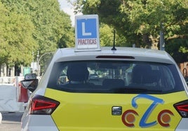 Un vehículo de autoescuela se para ante un semáforo.
