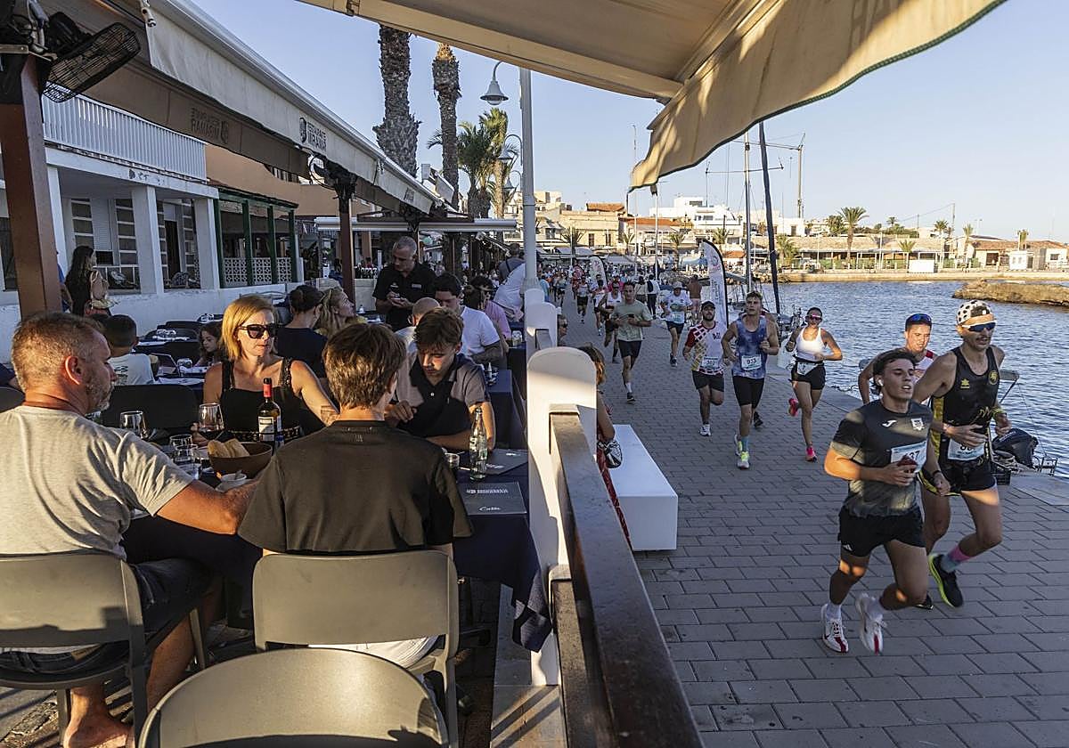 Los corredores avanzando por el paseo de Cabo de Palos, con las terrazas llenas, este sábado.