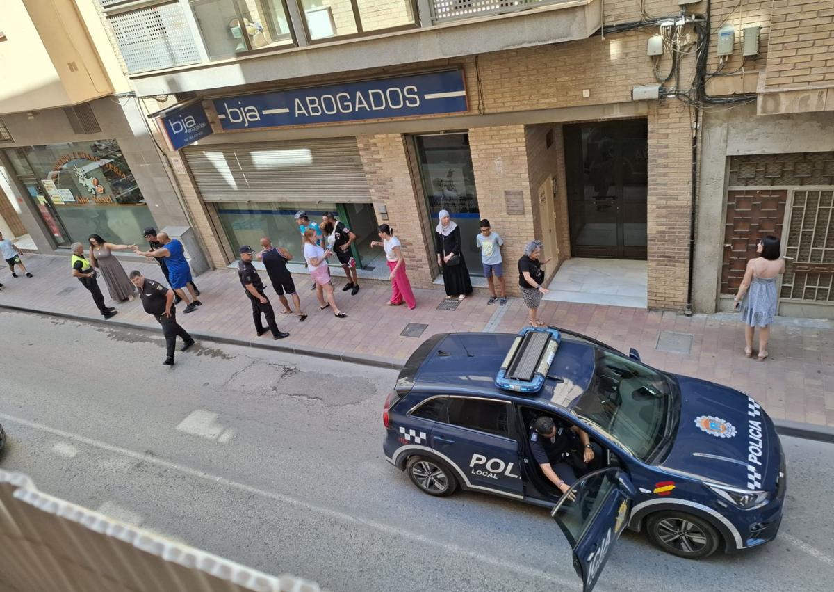 Imagen secundaria 1 - Arriba: Ana Rosell, dueña de la carnicería contigua al local, señala uno de los impactos de bala. Abajo: Fachada del despacho de abogados donde se produjeron los disparos y calle acordonada.