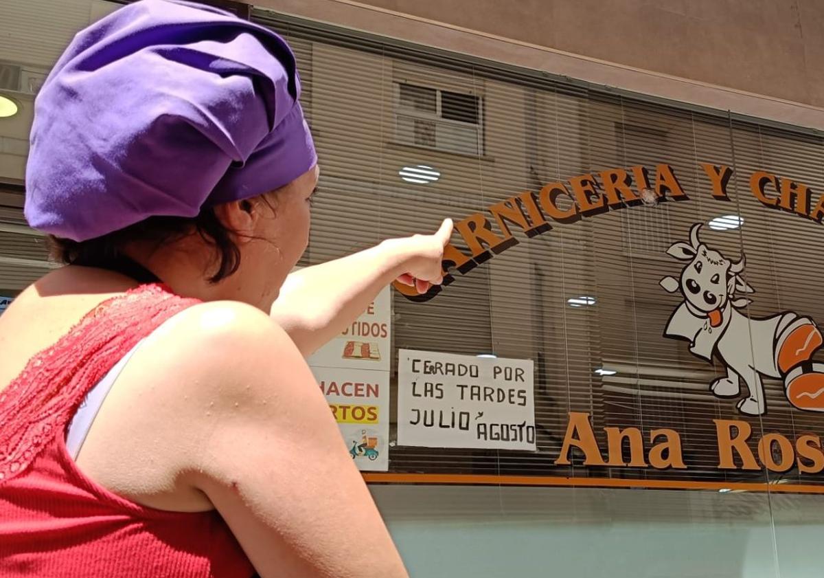 Imagen principal - Arriba: Ana Rosell, dueña de la carnicería contigua al local, señala uno de los impactos de bala. Abajo: Fachada del despacho de abogados donde se produjeron los disparos y calle acordonada.