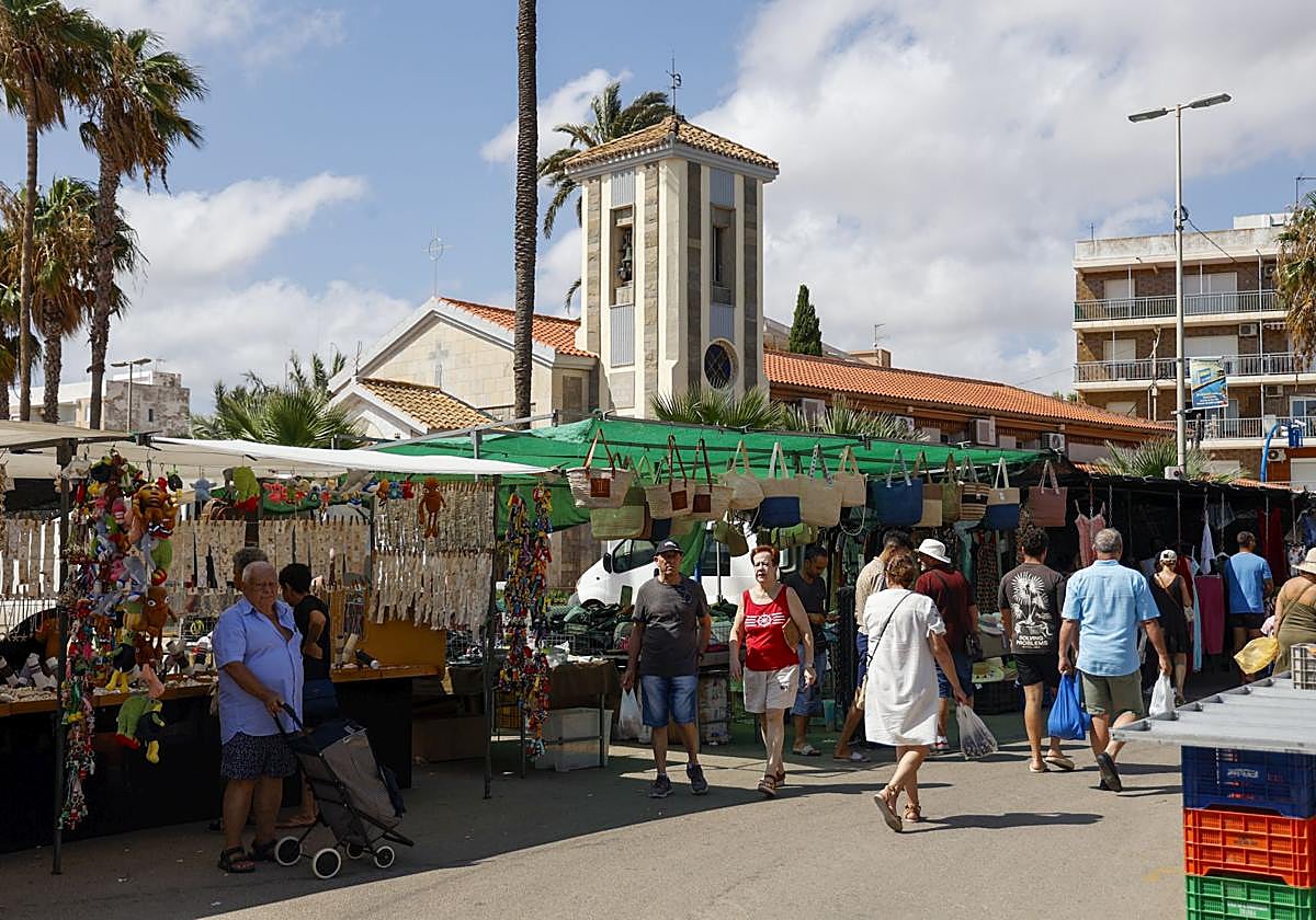 Vecinos y veraneantes de Los Urrutias recorren los puestos del mercadillo de la localidad de la ribera sur del Mar Menor.