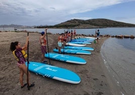 Varios jóvenes aprenden a practicar 'paddle' surf.