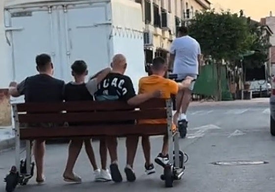 Los cuatro jóvenes sentados en el banco vandalizado.