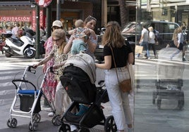Una mujer mayor pasa junto una madre con un bebé.