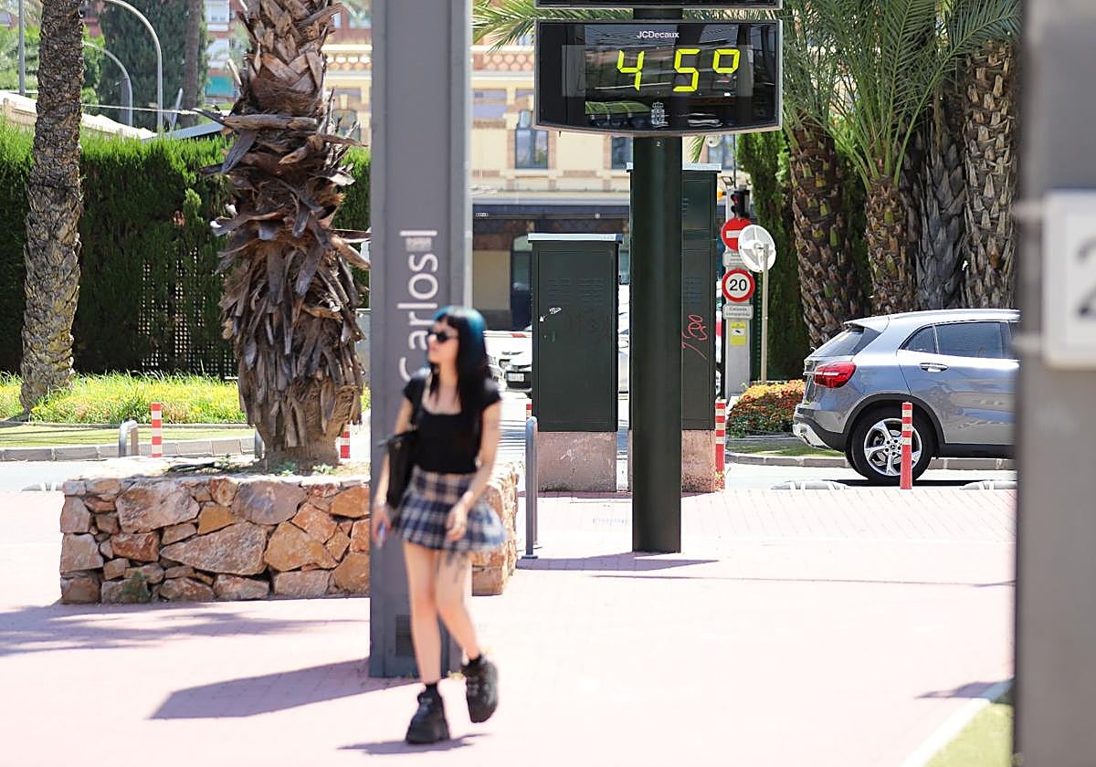 Una joven pasa junto a un termómetro en el centro de Murcia.