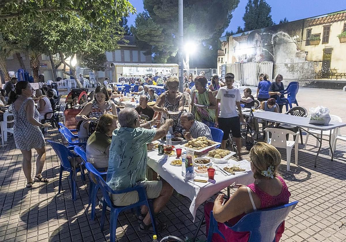 Los vecinos, de comida popular este pasado martes, en la plaza Pico Roldán y con el mural romano parcialmente calcinado, al fondo.