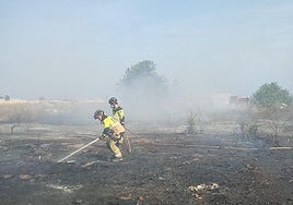 Dos bomberos apagan los rescoldos del fuego declarado este martes en San Javier.