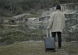 Uno de los fotogramas de la película, con Daniel tirando de su maleta hacia un lago.