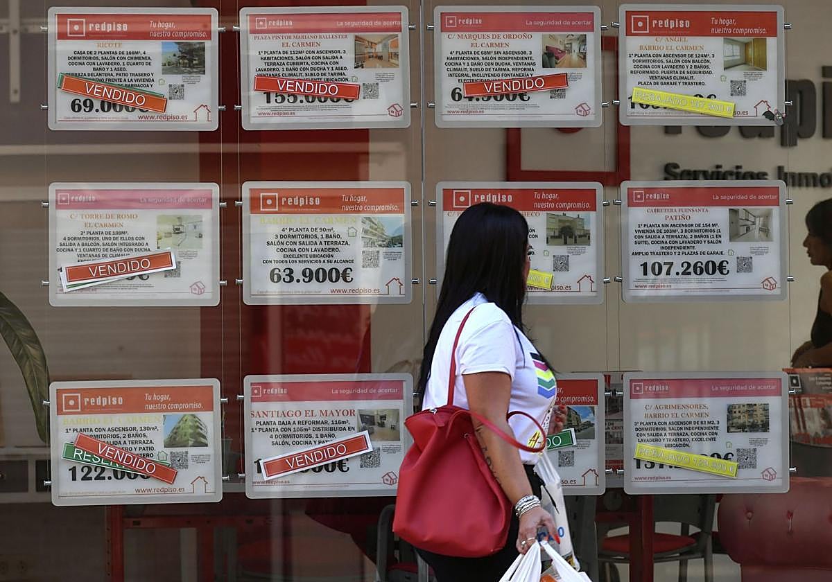 Una mujer revisa anuncios de venta de viviendas en una inmobiliaria.