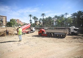 Varios camiones bañera depositan tierra en la parcela para proceder a su posterior relleno y compactación.