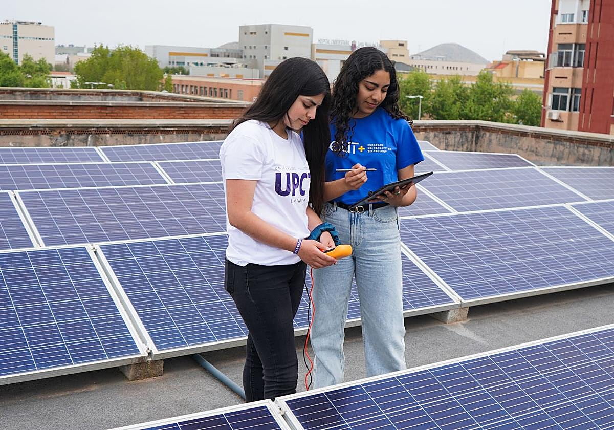 Dos estudiantes de la UPCT, junto a placas fotovoltaicas.