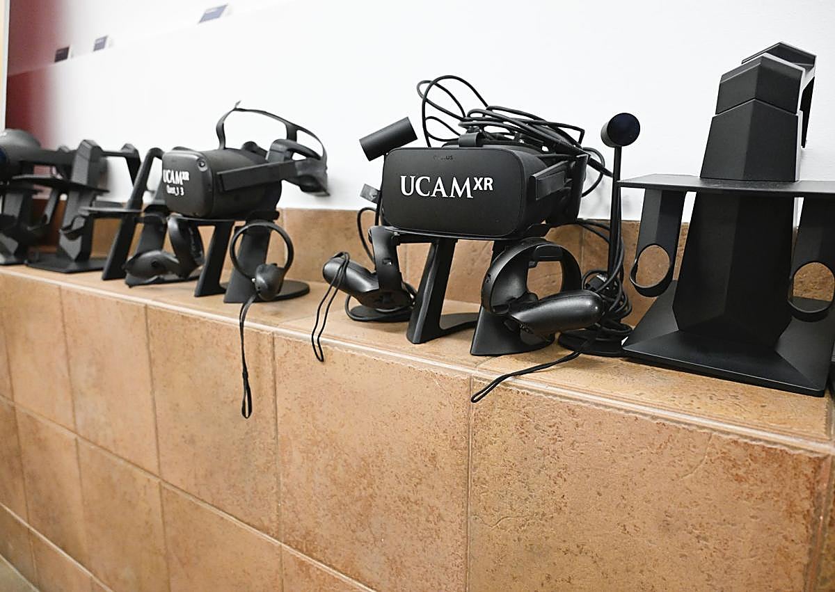 Imagen secundaria 1 - Arriba: Manuel Pardo coloca un chaleco háptico a Alberto Lanchares. Abajo: El profesor examina algunas de las gafas de realidad virtual de la UCAM.