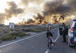 Un guardia civil impide el paso a un ciclista ante el incendio declarado en Torre de Rame, el jueves.