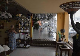 Una dependienta prepara unos estantes con varios tipos de lámparas.