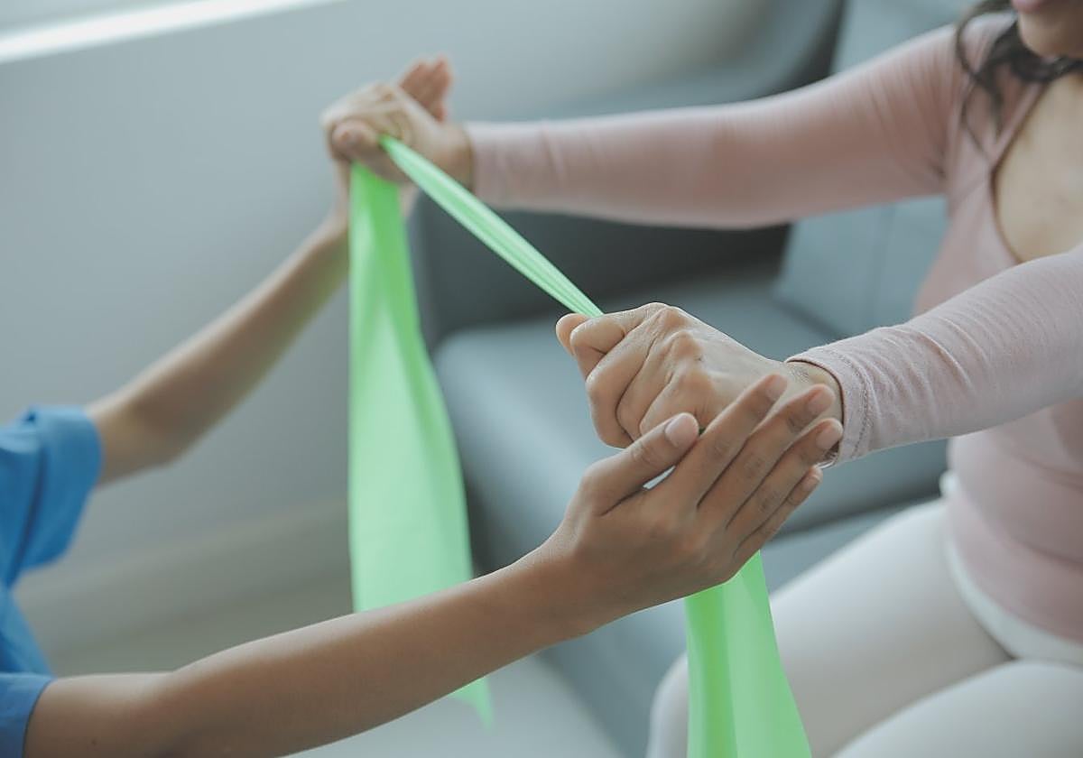Una fisioterapeuta realiza un ejercicio terapéutico con una paciente.