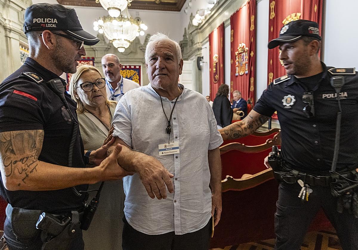 Dos policías locales escoltan fuera del salón de plenos al presidente de la Asociación de Vecinos del Sector Estación, Fulgencio Sánchez.