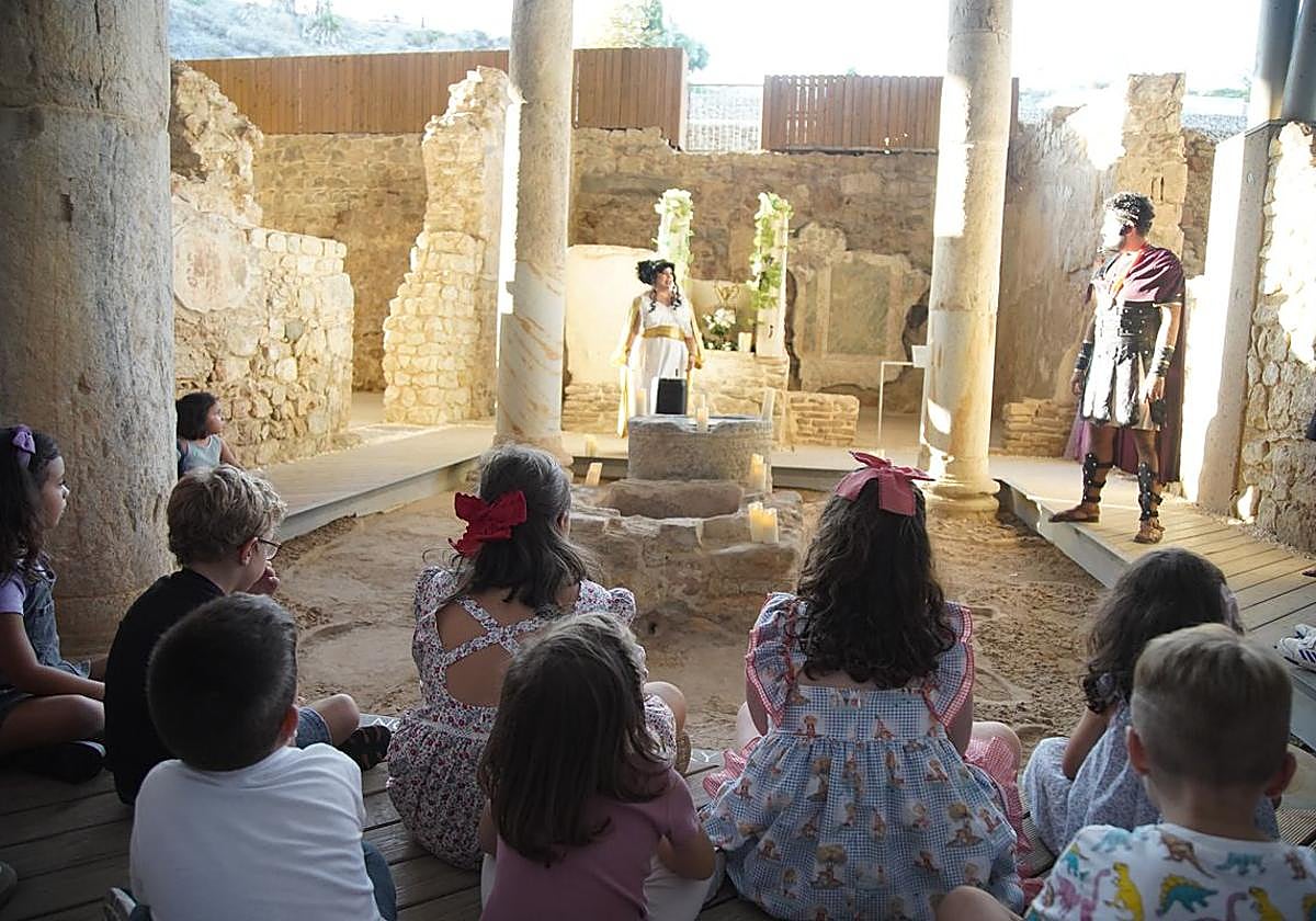 Festeros ataviado con sus trajes ante niños visitantes a uno de los centros.