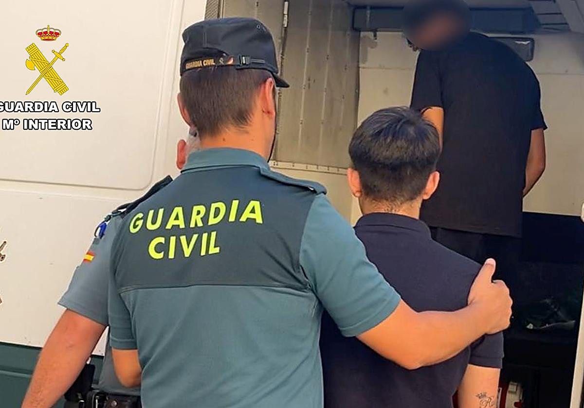 Un guardia civil conduce al furgón a uno de los detenidos.