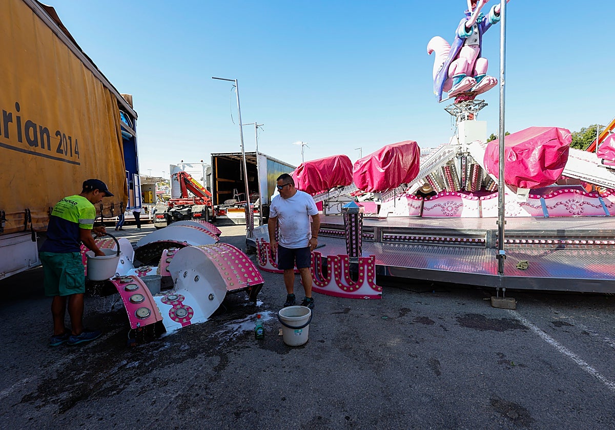 Feriantes limpian friegan las piezas del 'Canguro Loco' para su montaje en el Huerto de la Rueda.