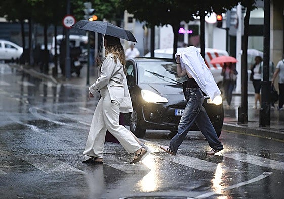 Dos viandantes bajo la lluvia en la Gran Vía de Murcia, en una imagen de archivo.