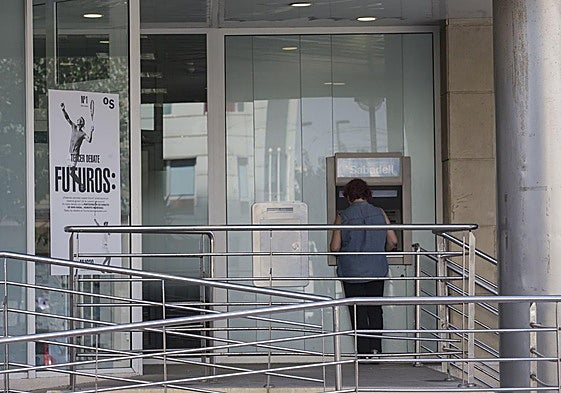 Una mujer sacando dinero de un cajero automático, en una imagen de archivo.