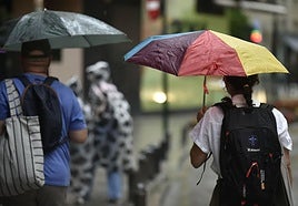 Dos personas pasean con paraguas por Murcia en un día de lluvia.