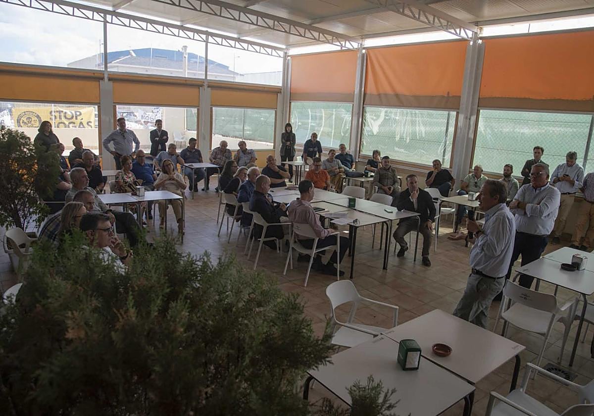 Fernando Sarasola explica el proyecto a los empresarios con las protestas vecinales al fondo.