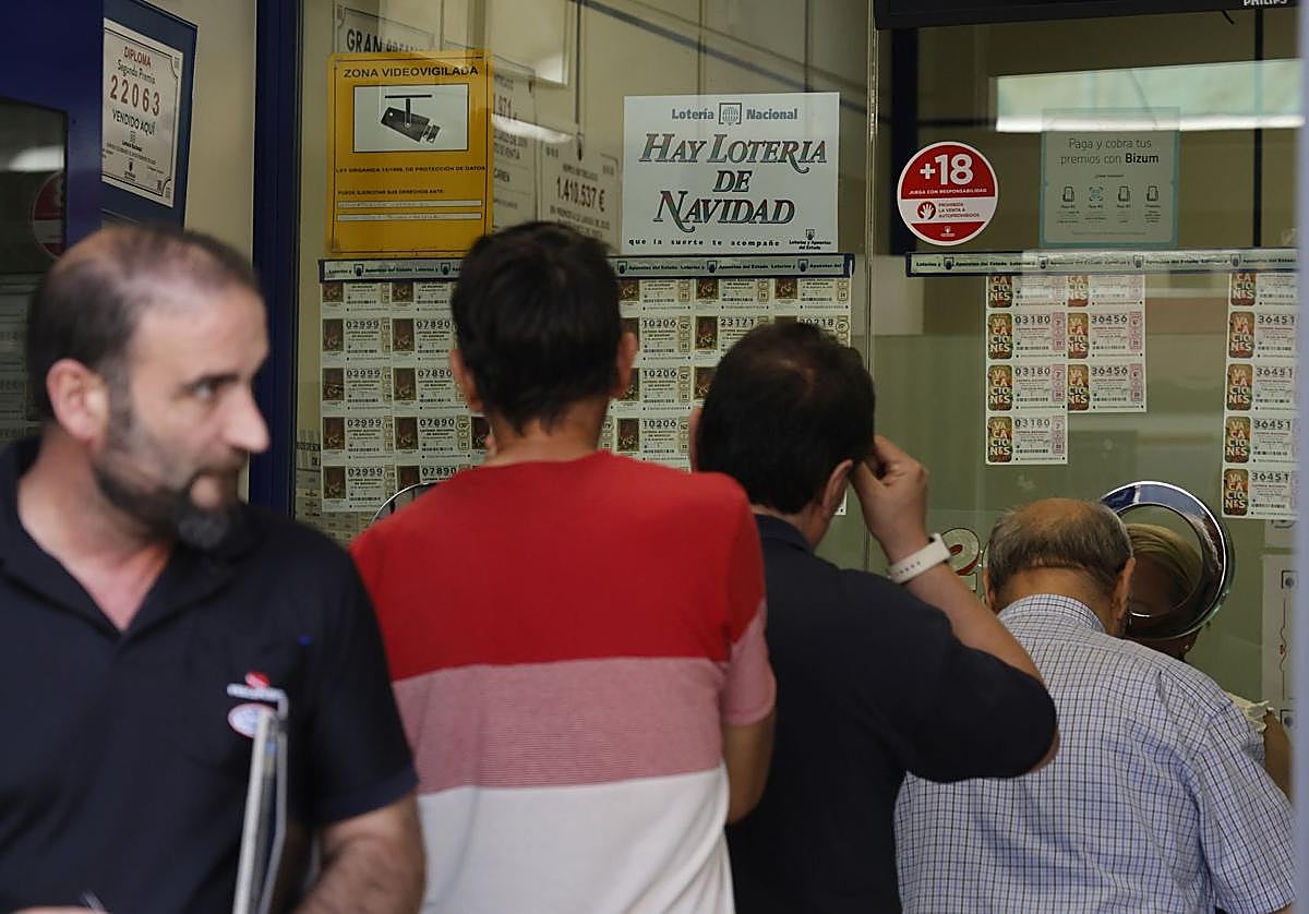 Ciudadanos hacen cola para comprar sus décimos de Lotería de Navidad en una administración.