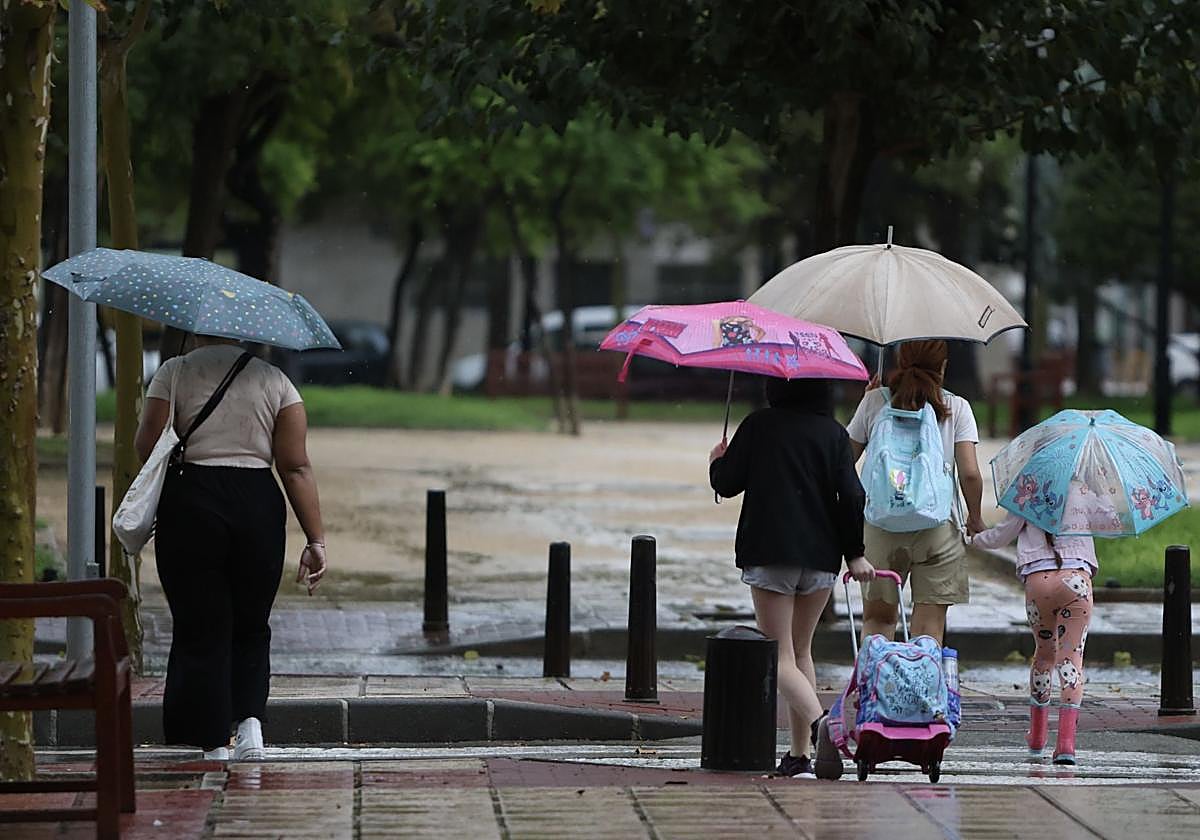 Dos mujeres y niñas con paraguas, este jueves, a la salida del colegio.