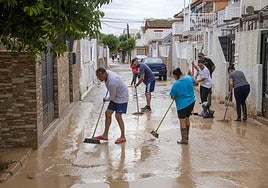 Varios vecinos de la 'zona cero' de Los Alcázares retiran el barro de sus patios y calles tras las inundaciones registradas durante la madrugada.