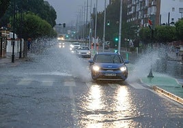 Coches avanzan por una calle de Cartagena inundada por las fuertes lluvias.
