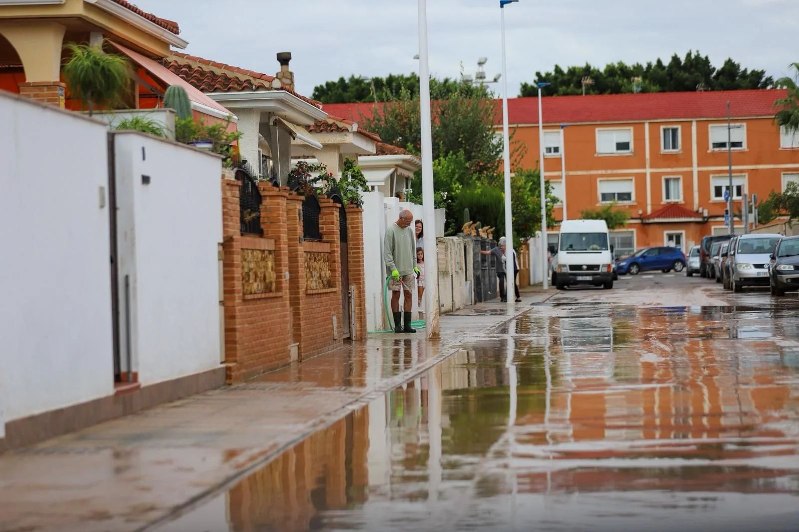 Unos vecinos de San Javier retiran el agua acumulada en su calle.