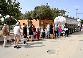 Vecinos de San Cayetano acuden a una cuba de abastecimiento con cubos y garrafas, este domingo.