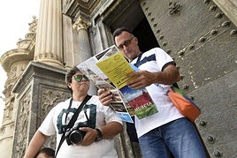 Unos turistas consultan un mapa junto a la Catedral de Murcia.