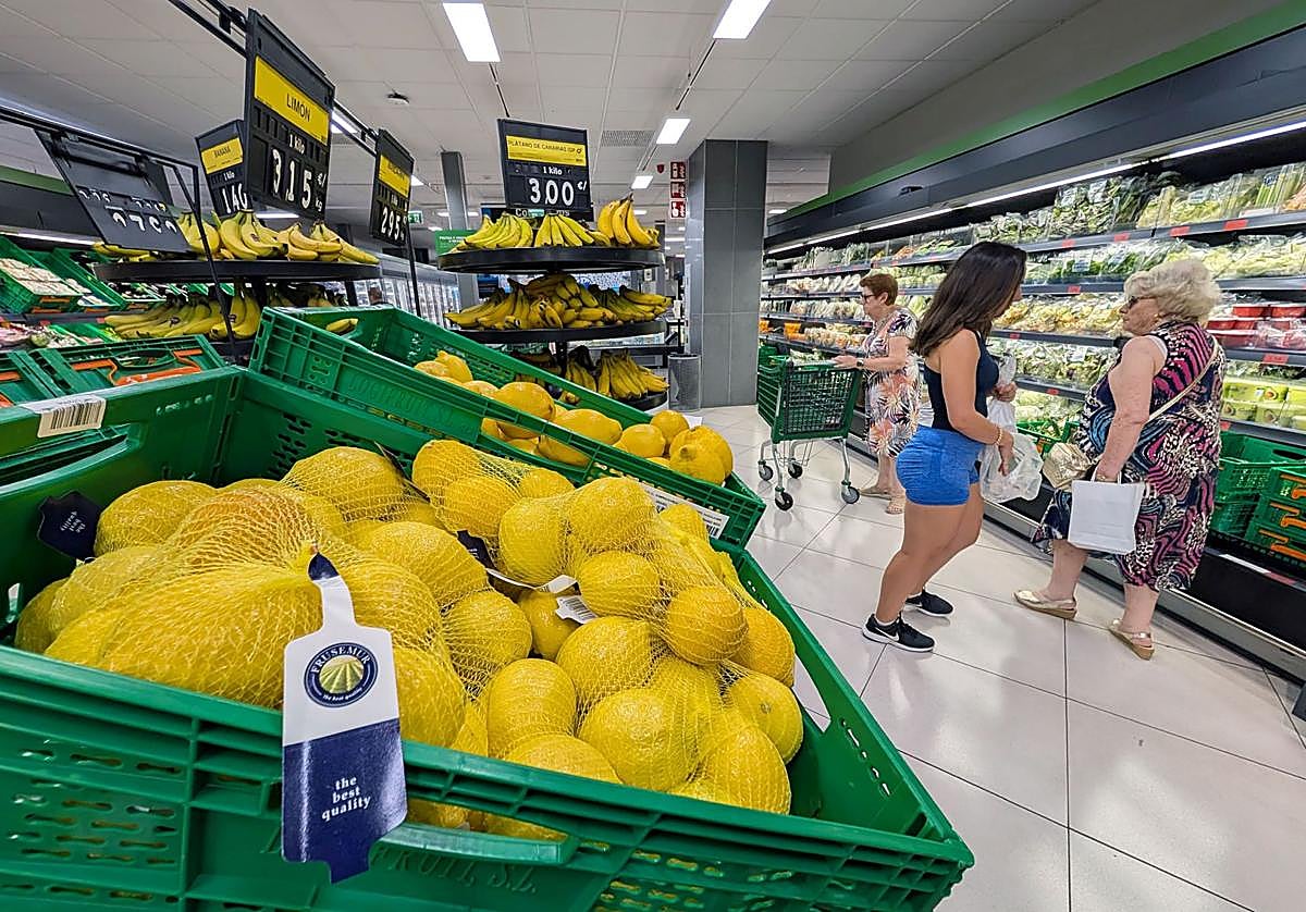 Varias clientas en la sección de frutería de un supermercado.