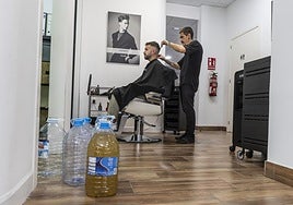 Imanol Oliver, ayer atendiendo a un cliente en la Peluquería Oliver, en Los Alcázares. En primer plano, varias botellas.