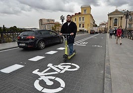 Un conductor de un patinete y varios coches, en el Puente Viejo de Murcia.