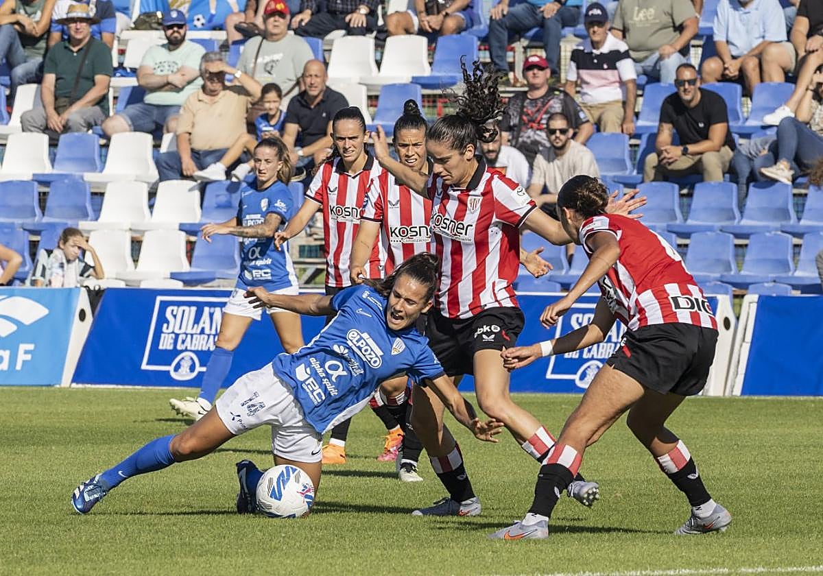 Ana Velázquez, en el suelo, ante dos jugadoras del Athletic.