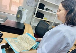 Una bibliotecaria observa los documentos que se restaurarán.