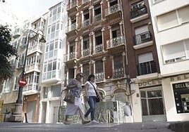 Dos personas pasan ante el edificio en rehabilitación.