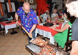 Pedro Lucas Abellaneda reparte marisco con una pala en la mesa de un grupo de comensales.