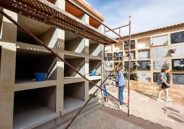 Una mujer con un ramo de flores junto a uno de los bloques de nichos en reconstrucción, ayer.