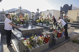 Una familia coloca los ramos y centros de flores sobre dos de los enterramientos del cementerio de San Ginés de la Jara.