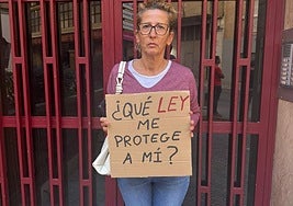 Ana muestra un cartel de protesta en la entrada del edificio donde está su casa ocupada por su inquilina.