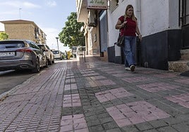 Una vecina pasea por la calle Salado, donde las aceras presentan losas resquebrajadas y un firme muy irregular.