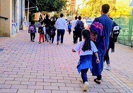 Familias caminan por la alameda de Cervantes a la salida del colegio.