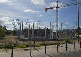 Una joven pasea a su perro frente a las obras de construcción de la nueva Escuela Infantil del parque de la Rosa, que se encuentran en un estado muy avanzado.