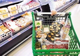 Un cliente carga el carrito con productos de charcutería de Mercadona.